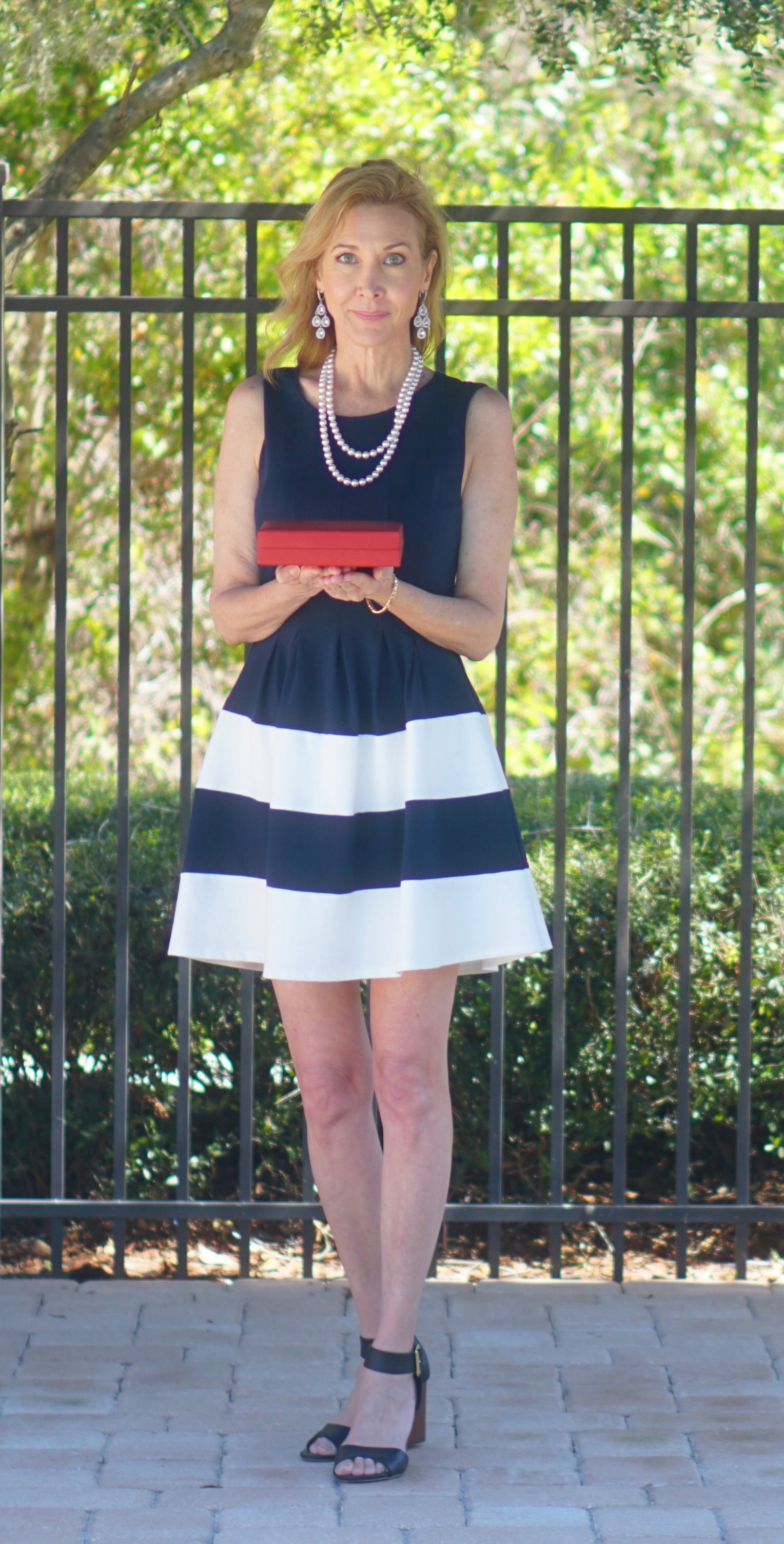 woman wearing black striped dress holding red box