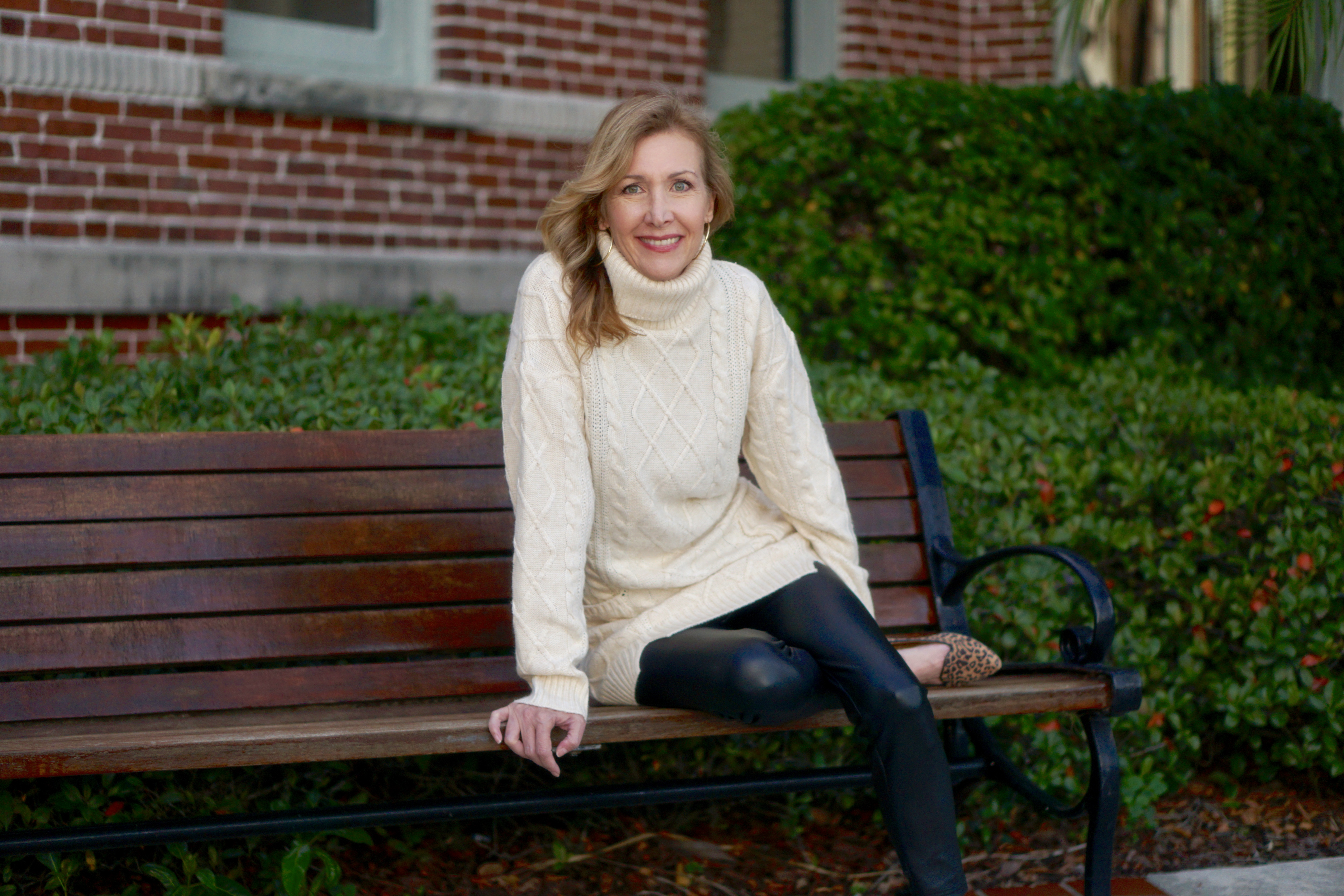 Woman wearing cream colored knit sweater sitting on a bench