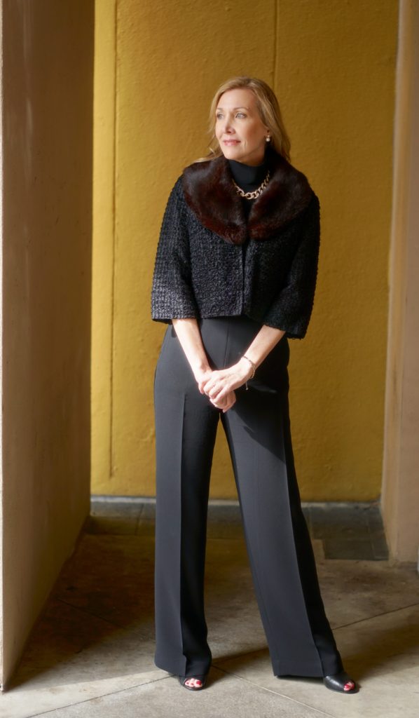 Woman wearing fur cuffed sweater overtop of black pants