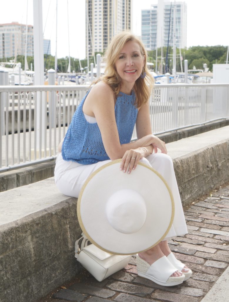 Smiling blogger wearing blue knit shirt and white pants