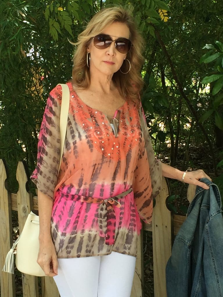 How to Build Your Wardrobe by popular Florida mature fashion blog: image of a woman wearing white pants with a orange, pink and brown chiffon top. 