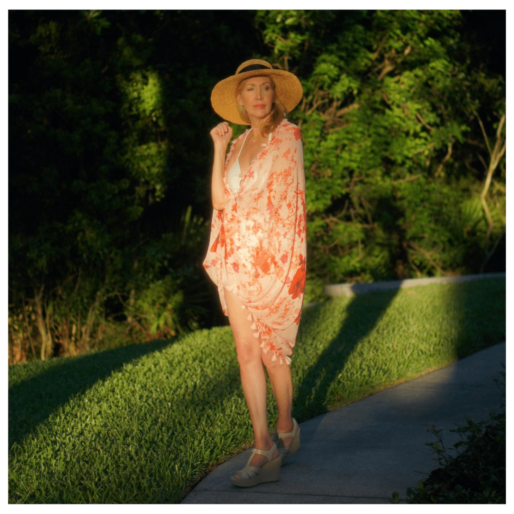 How to Lose Weight Over 50 by popular Florida mature lifestyle blog, Sharing a Journey: Pinterest image of a mature woman wearing a white swimming suit, pink and red tassel wrap, and straw sun hat. 