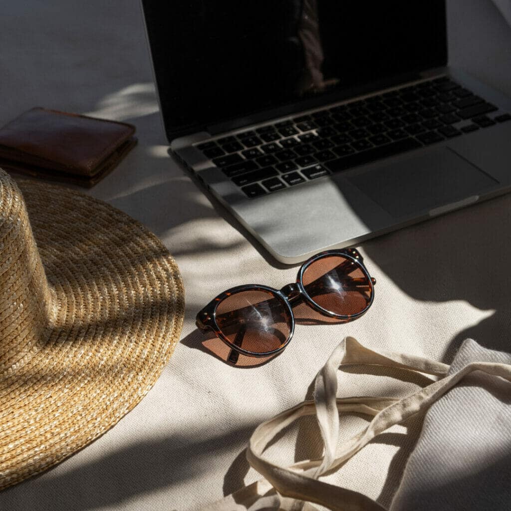 Laptop, hat, wallet and sunglasses in a sunbeam