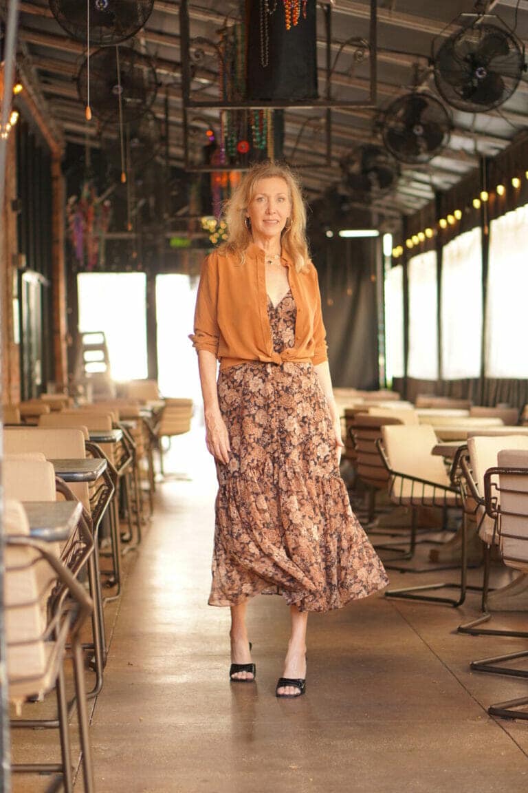 Nina Anders, Over 60 Influencer wears brown floral dress with chestnut colored blouse tied at the waist.