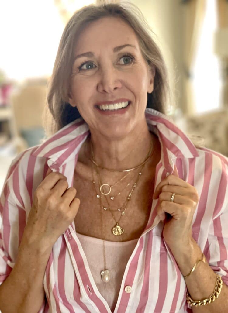 Nina Anders top fashion blogger over 50 wears a pink and white striped button down shirt